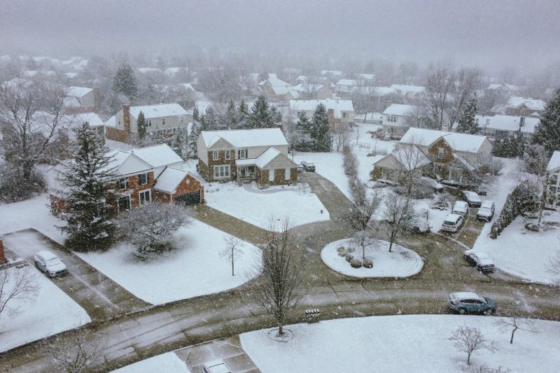 Aerial view of a quiet suburban neighborhood covered in snow on a winter day.