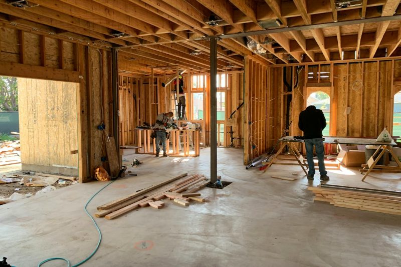Workers actively constructing a house frame, highlighting interior carpentry and the building process in a residential setting.