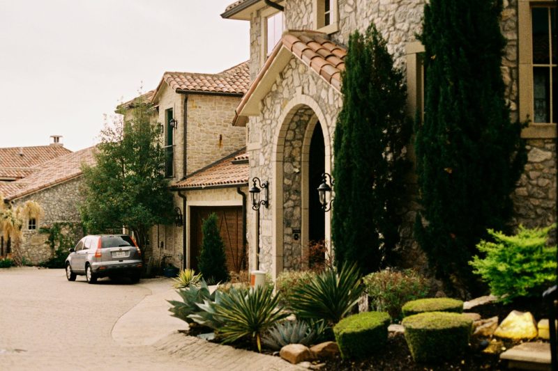 Elegant stone mansion surrounded by greenery with a gated entry in Dallas, Texas.