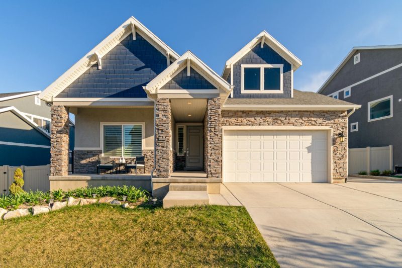 Charming modern suburban home with a stone facade and a neatly maintained lawn.