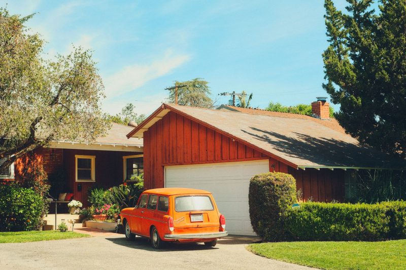 Classic orange car parked in a lush suburban driveway in Los Angeles.